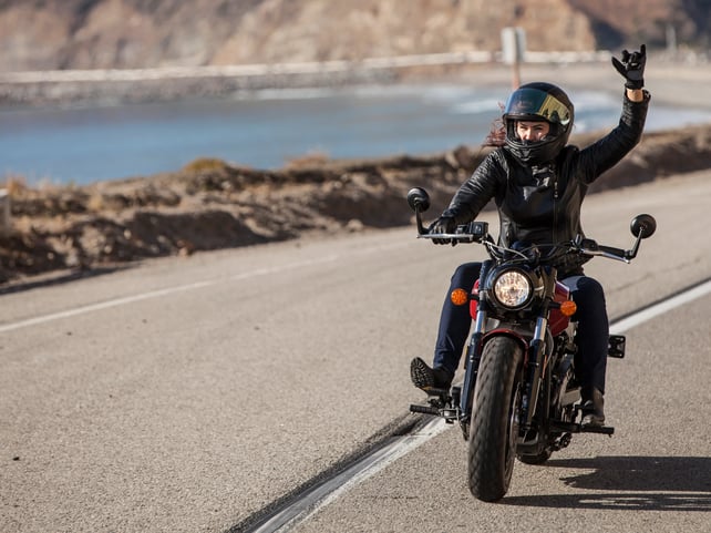 Confident woman riding her motorcycle on open highway, embracing freedom and adventure on the road