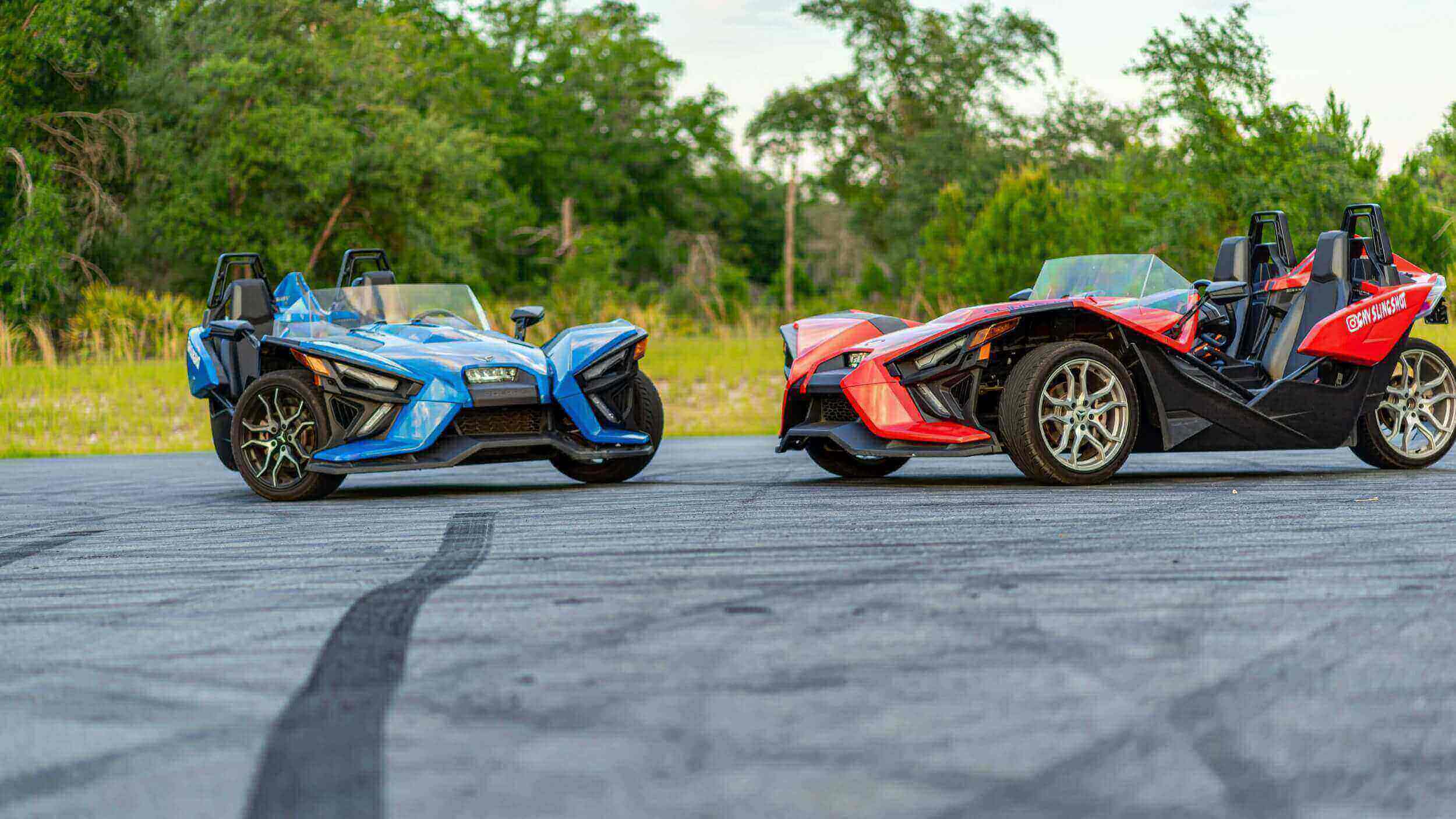 Two Polaris Slingshot rental vehicles parked side-by-side in a parking lot