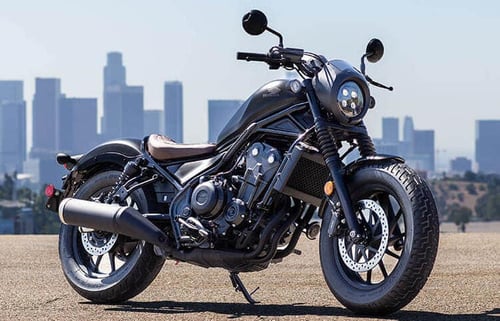 A closeup of the 2021 Honda Rebel 1100, that feautres a tan seat, charcoal paint job and classic cruiser stylings. 