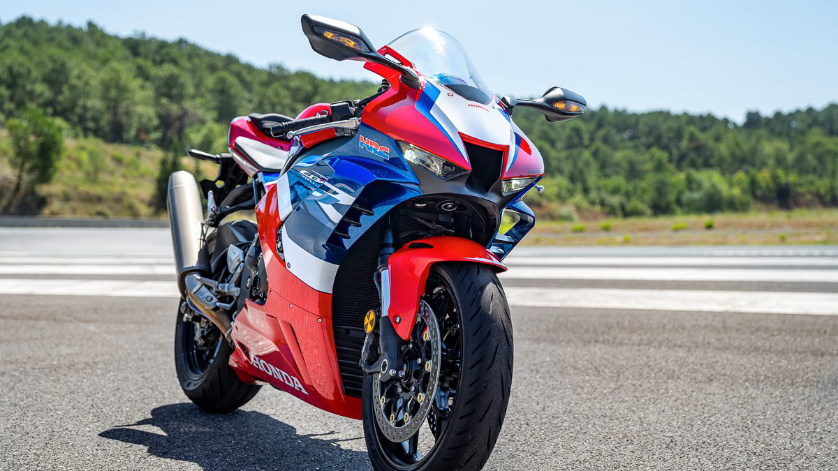 The 2021 Honda CBR1000RR Fireblade show parked at a racetrack that is surrounded by a green forest. 