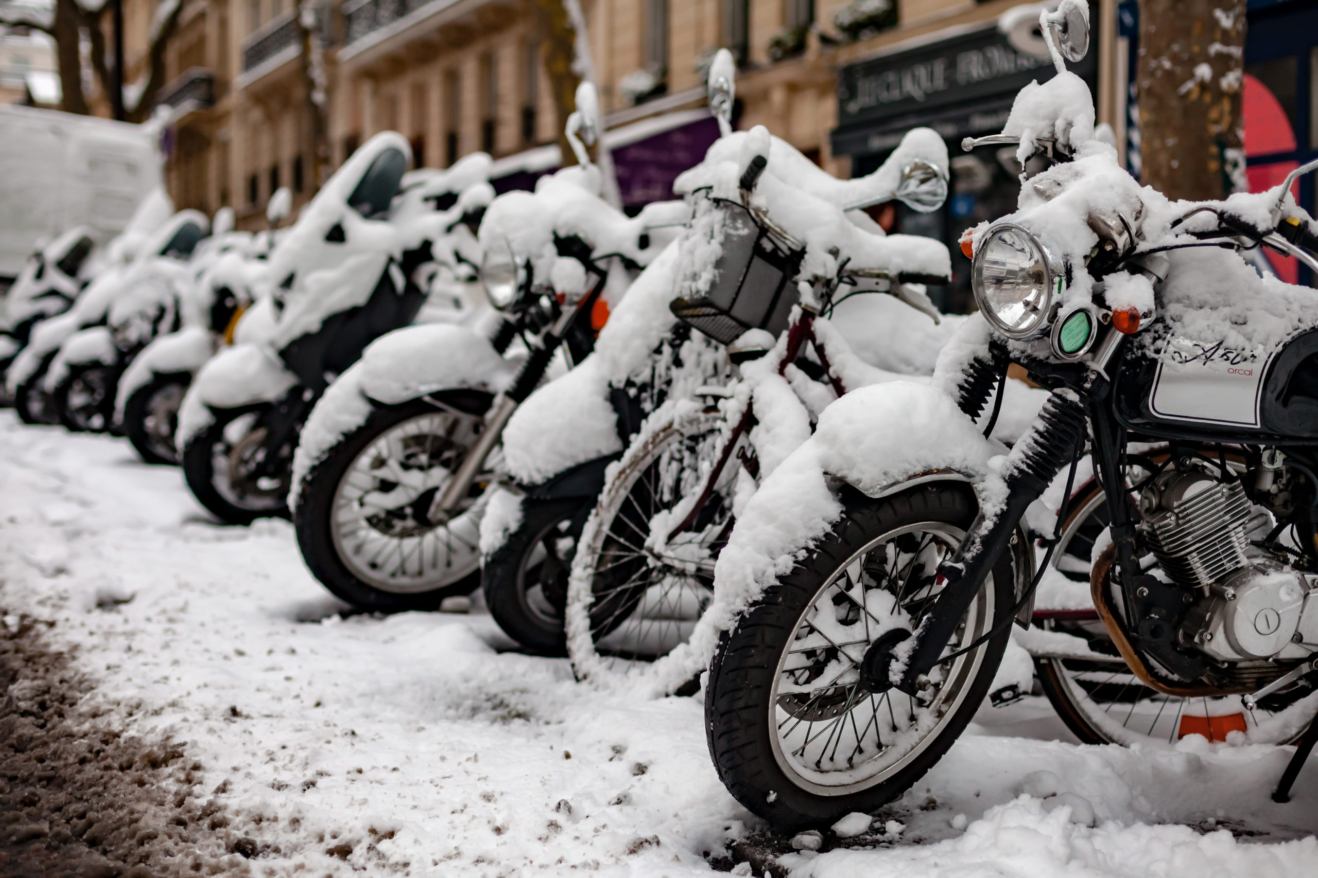Row of snow-covered motorcycles parked outside a winter business