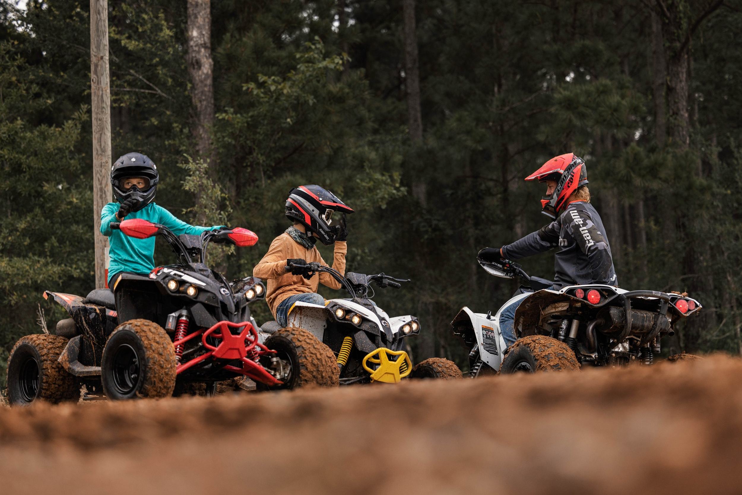 Three enthusiastic kids enjoying an exhilarating ride on the best youth ATVs along a rustic wooden mud trail