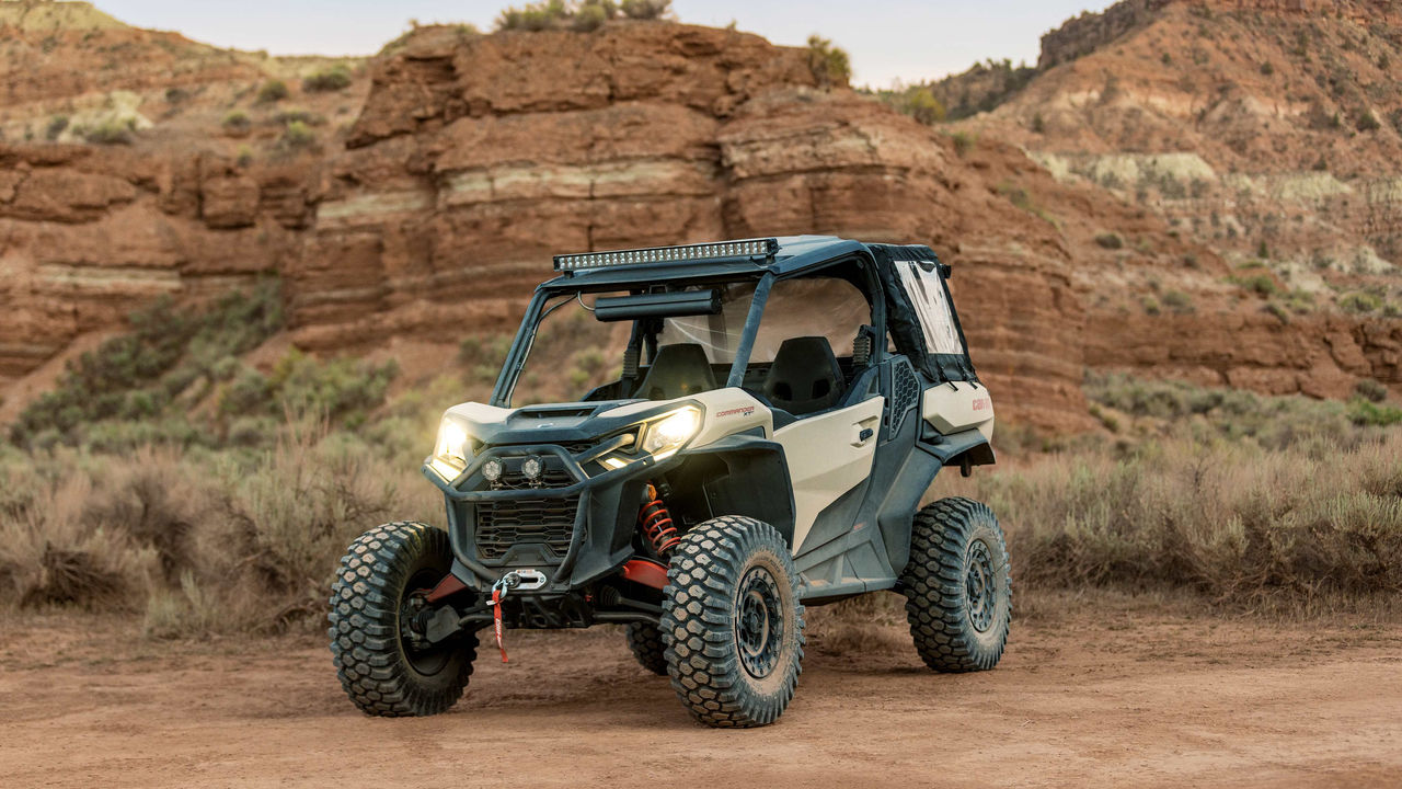 Can-Am side-by-side parked on sandy terrain with mountain range in the background - perfect off-road adventure vehicle.