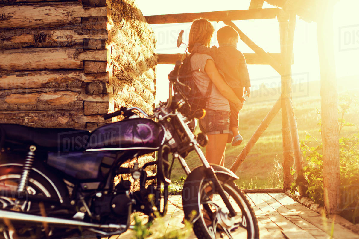 Mother and child enjoying sunset on porch with motorcycle