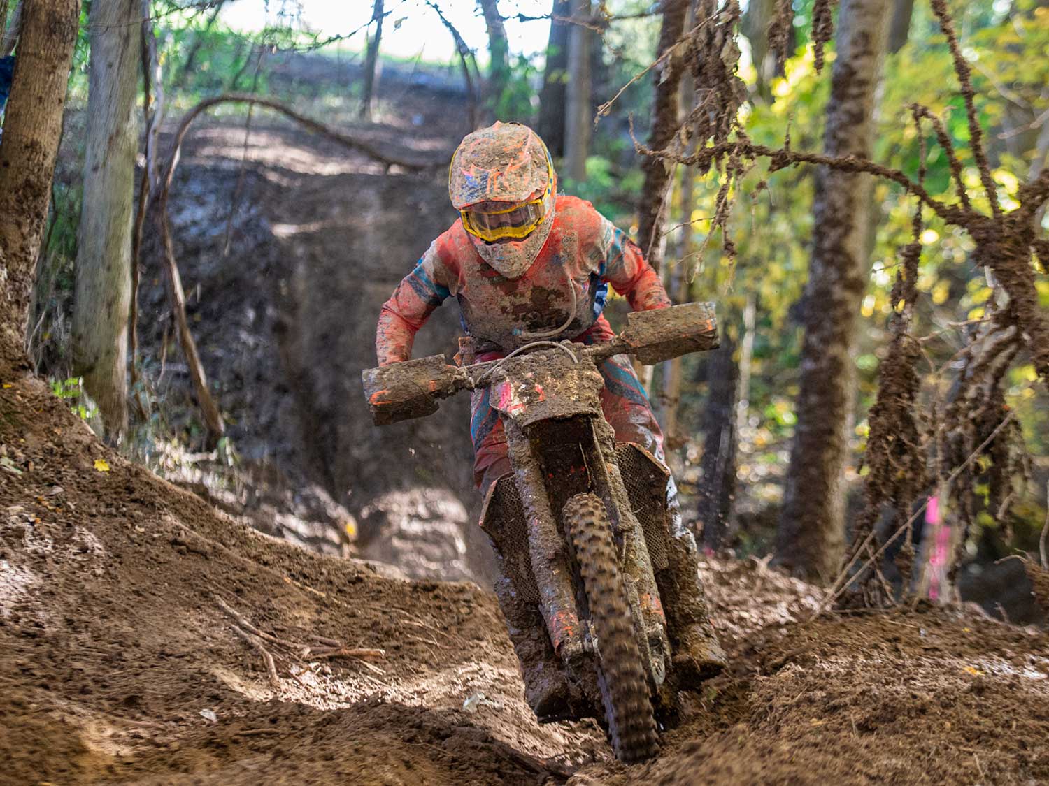 Rider on off-road motorcycle navigating muddy terrain at high speed