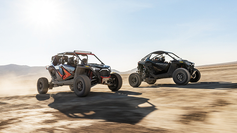 A pair of two off-road side by sides racing through an off-road desert track. 